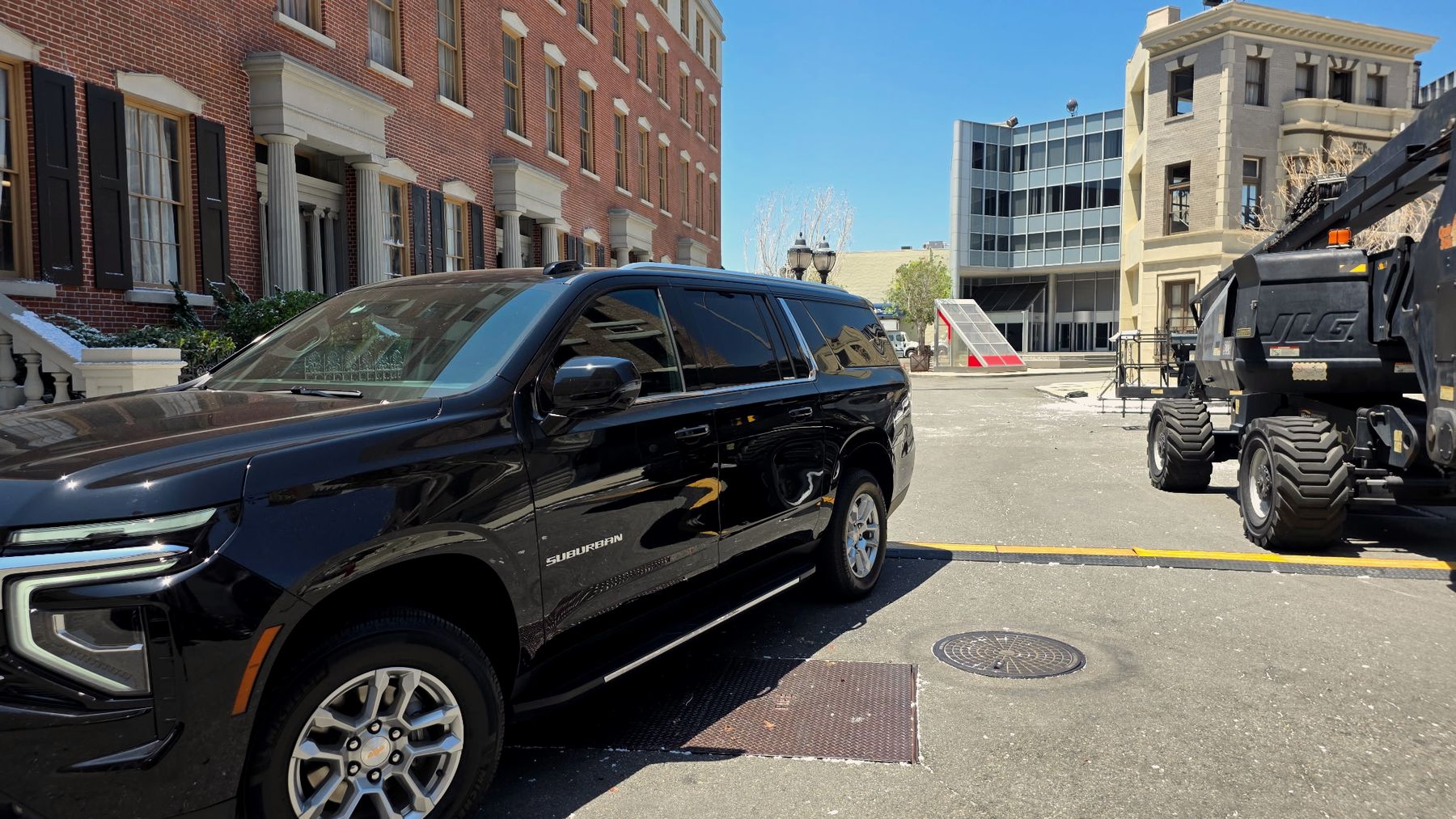 Side view of the black Chevrolet Suburban beside brick townhouse facades on a studio backlot